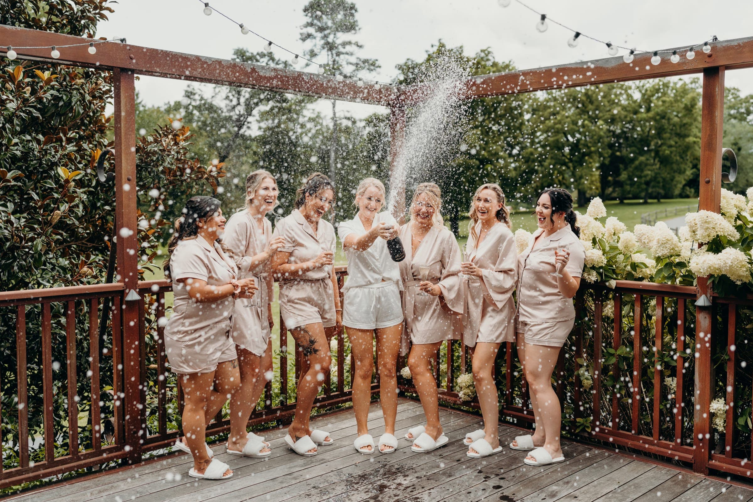 The wedding party celebrating together with champagne on a string-lit terrace.