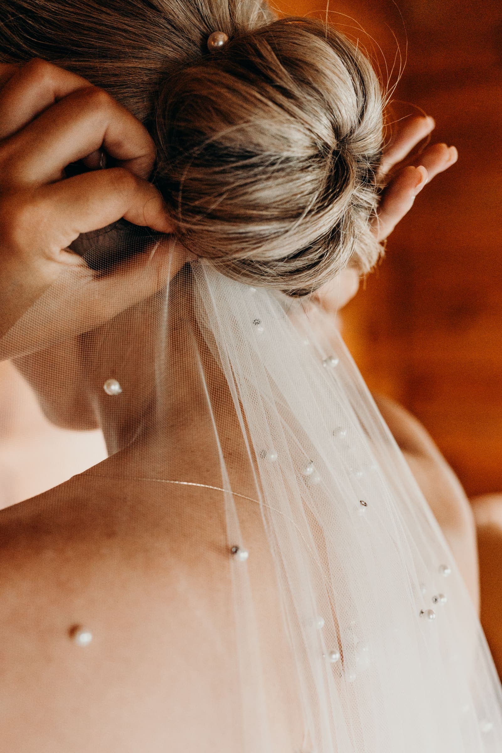 A bride in a delicate pearl veil, photographed in soft, natural light.